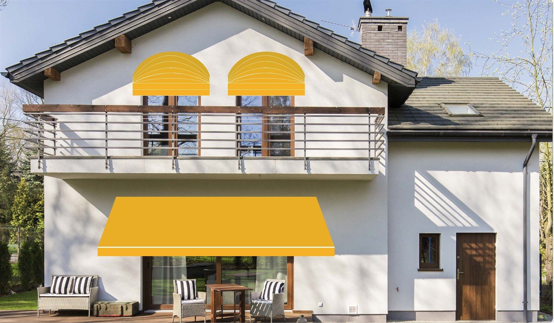 Two-story house with balcony and yellow awnings over windows and patio area, surrounded by trees.